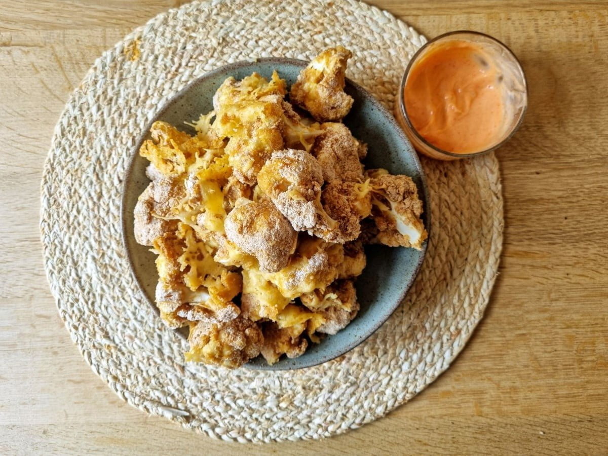 Bloemkool nuggets op een bord met dipsaus.