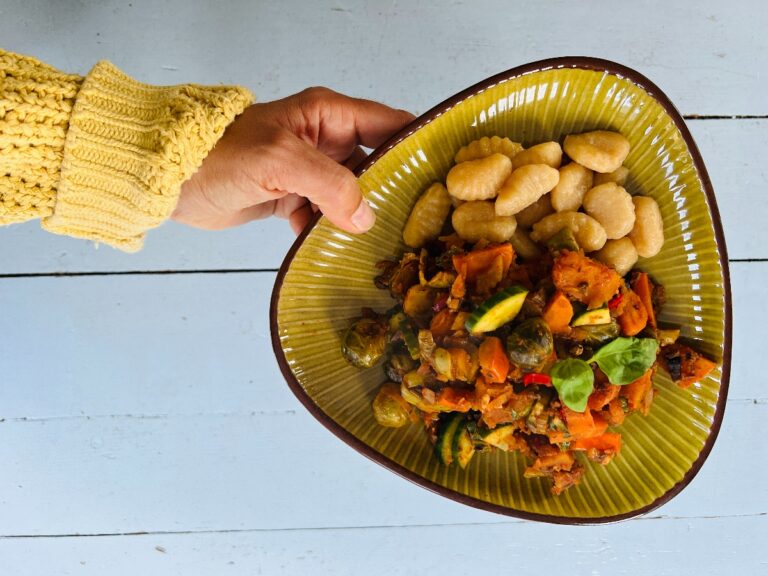 Mooi opgemaakt bord met gnocchi met groenten zoals spruitjes in tomatensaus.