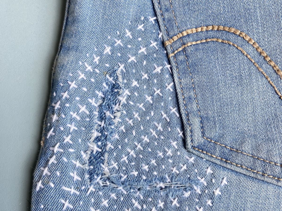 Sashiko mending: groot gat in kledingstuk met lapje stof repareren.